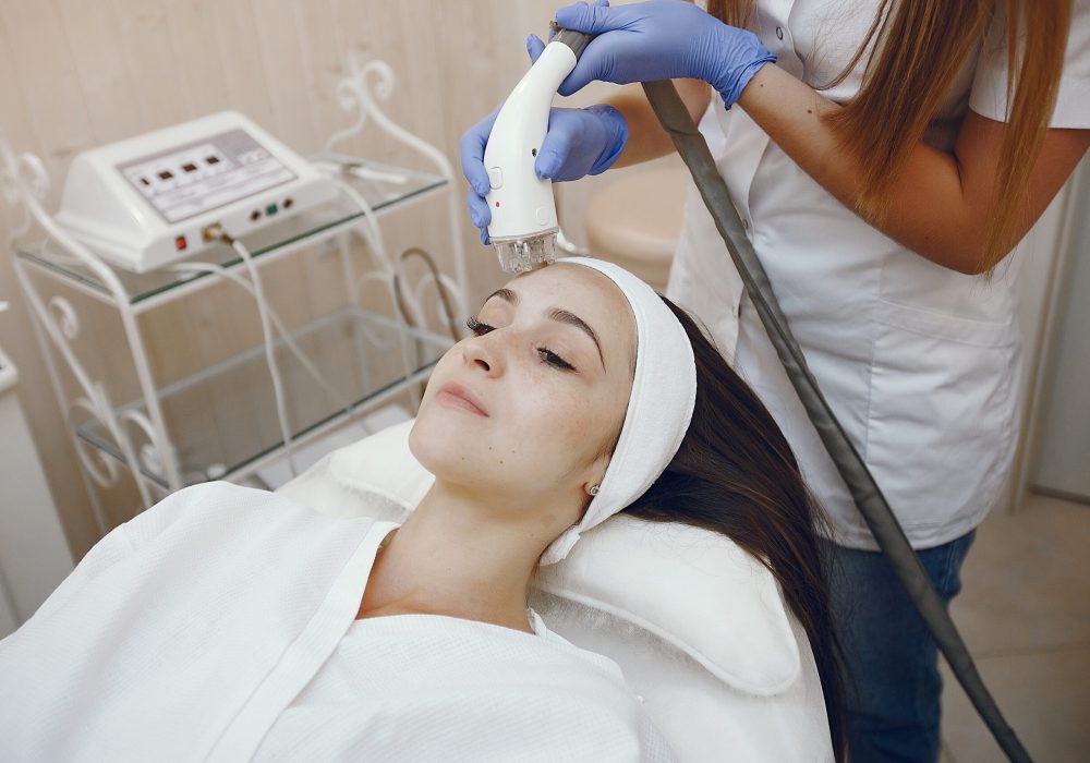 Cosmetologist use laser. Woman with cosmetologist. Lady in a beauty studio.
